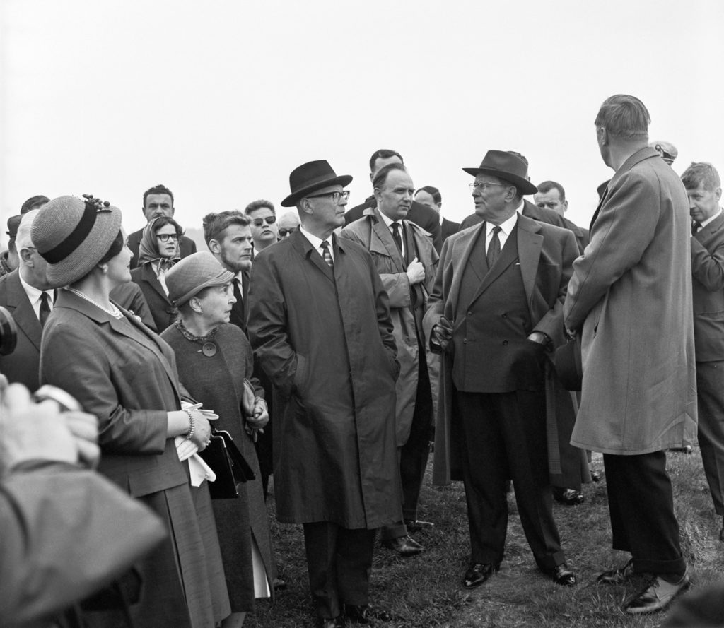 Herrar och damer utomhus i sommarkappor och i hatt, svartvitt fotografi.