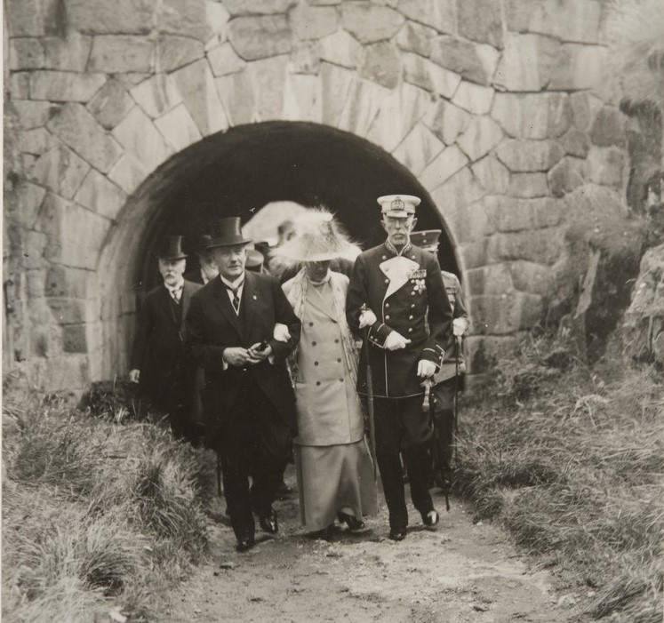 Högtidsklädda människor träder ut genom ett valv 1925