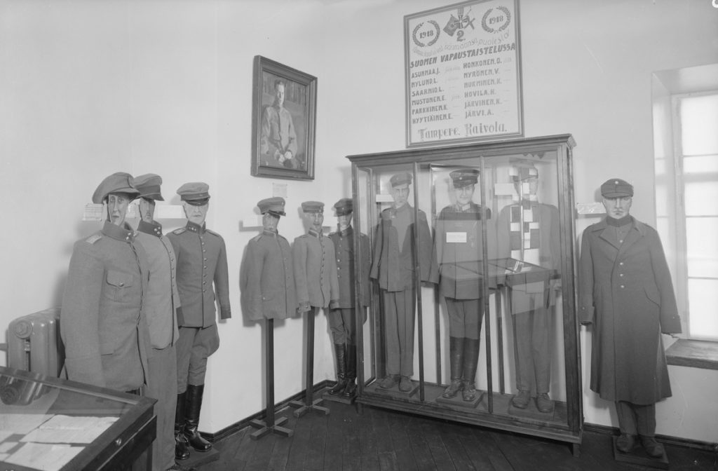 Svartvitt foto. Militäruniformer uppställda på mannekängdockor i gammalt museum.