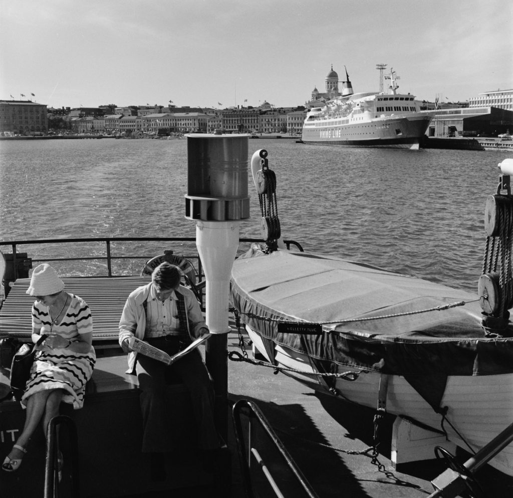 Man och kvinna på en passagerarfärja som åker ut från staden.