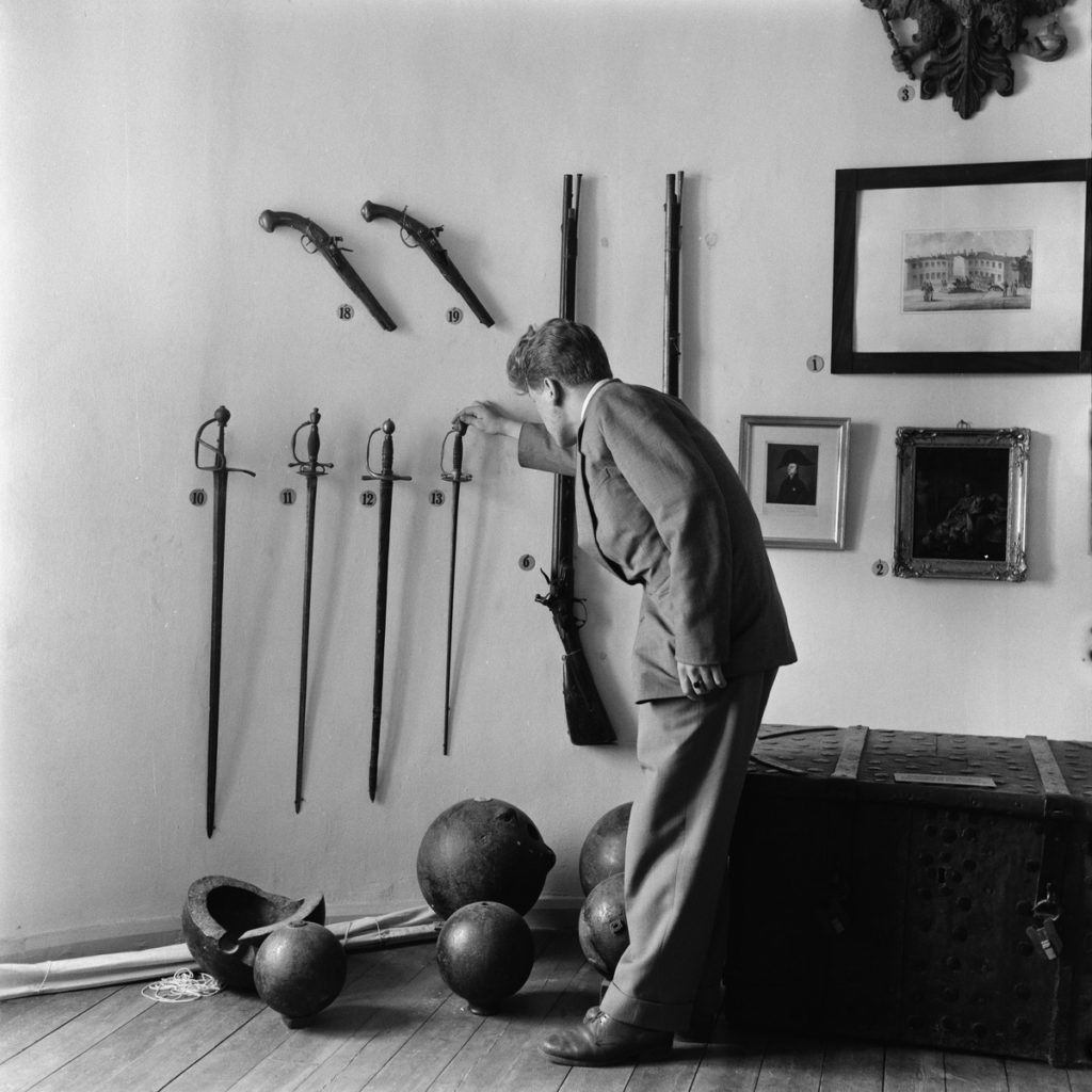 Man står lätt framböjd och tittar på utställda historiska vapen på ett museum.